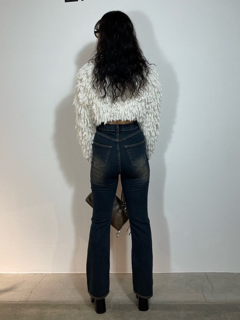 ホワイト系のニット/セーター、ブルー系のデニムパンツ、ブラウン系のショルダーバッグを着用したレディースの秋コーディネートの3枚目の写真