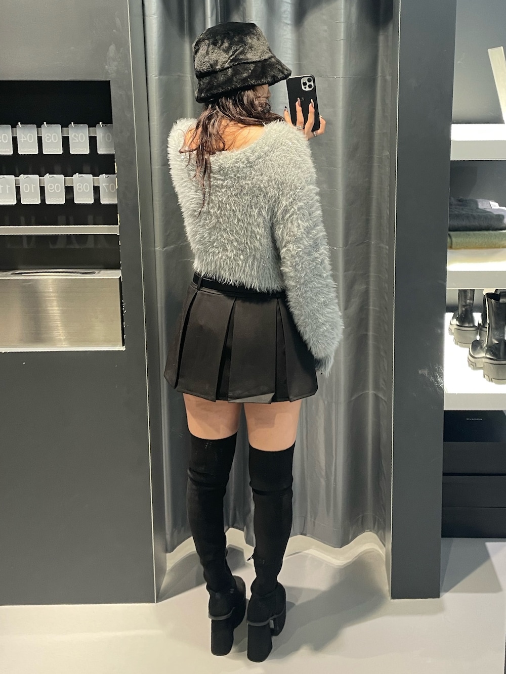 グレー系のニット/セーター、ブラック系のスカート、ブラック系のブーツを着用したレディースの秋コーディネートの3枚目の写真