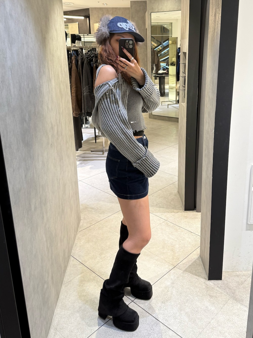 グレー系のニット/セーター、ブルー系のスカート、ブラック系のブーツを着用したレディースの秋コーディネートの2枚目の写真