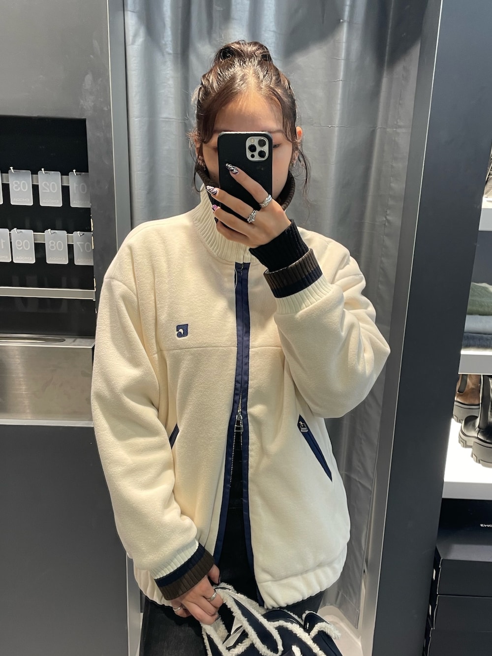 ホワイト系のブルゾン、ブルー系のハンドバッグ、ブラック系のデニムパンツを着用したレディースの秋コーディネートの4枚目の写真