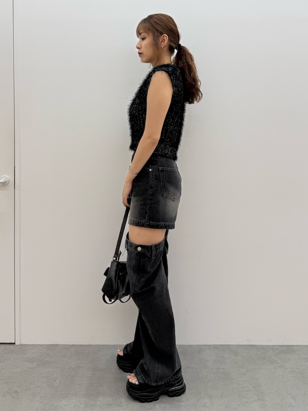 ブラック系のニット/セーター、ブラック系のデニムパンツ、ブラック系のハンドバッグを着用したレディースの夏コーディネートの2枚目の写真