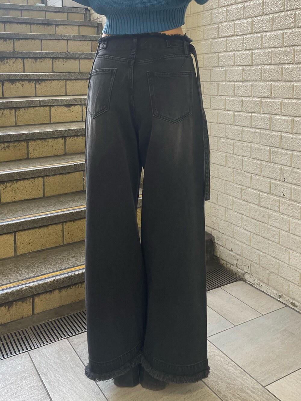 ブルー系のニット/セーター、ブラック系のデニムパンツ、ブラック系のブーツを着用したレディースの春コーディネートの9枚目の写真