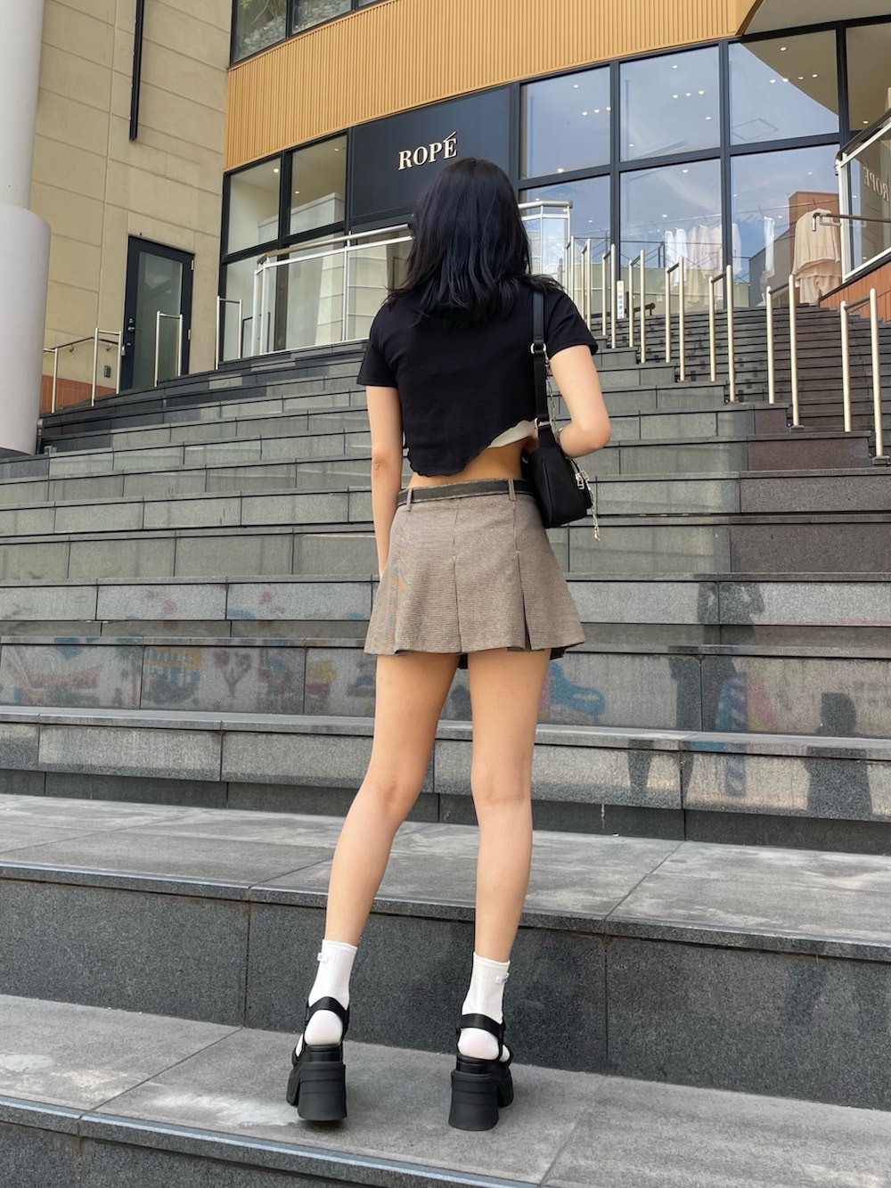 ブラック系のサンダル、ブラック系のTシャツ/カットソー、ブラック系のハンドバッグを着用したレディースの夏コーディネートの6枚目の写真