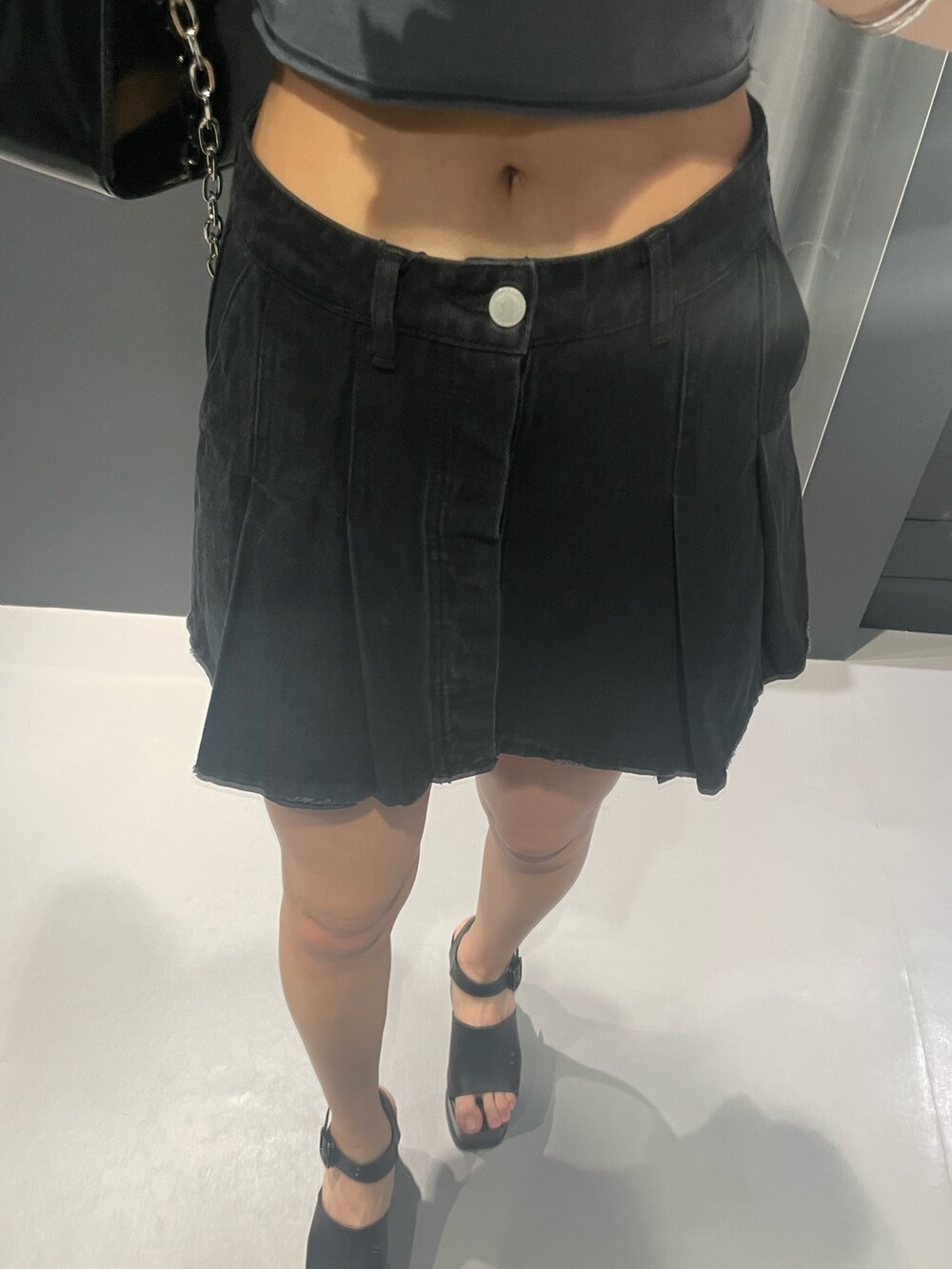 グレー系のTシャツ/カットソー、ブラック系のデニムスカート、ブラック系のショルダーバッグを着用したレディースの春コーディネートの6枚目の写真