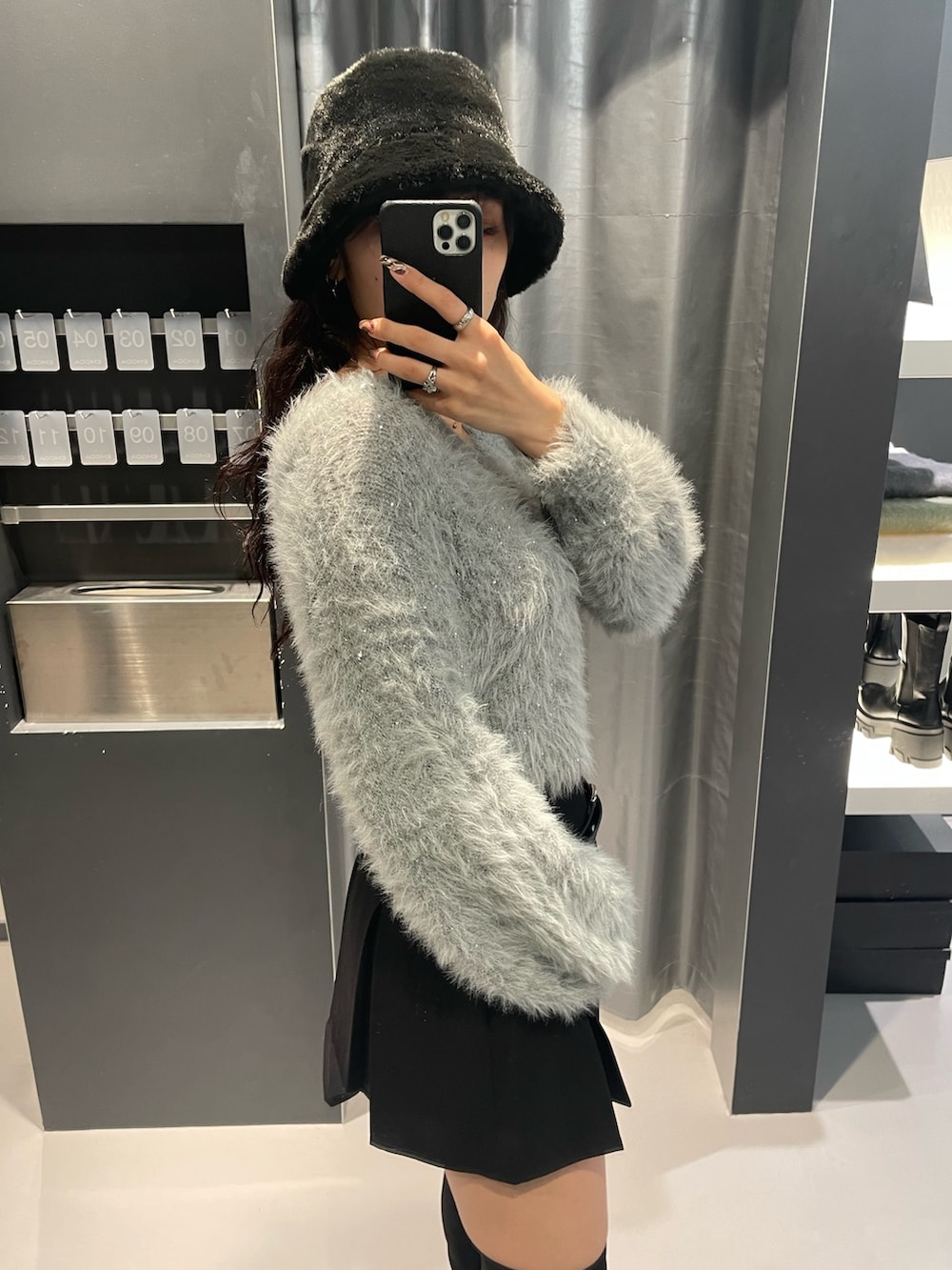 グレー系のニット/セーター、ブラック系のスカート、ブラック系のブーツを着用したレディースの秋コーディネートの5枚目の写真