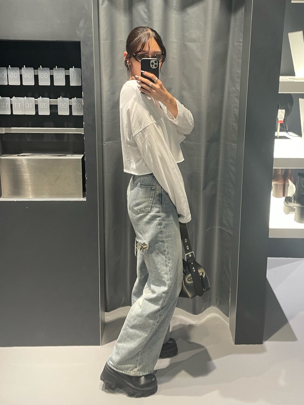 ホワイト系のTシャツ/カットソー、ブルー系のデニムパンツ、ブラック系のハンドバッグを着用したレディースの秋コーディネートの2枚目の写真