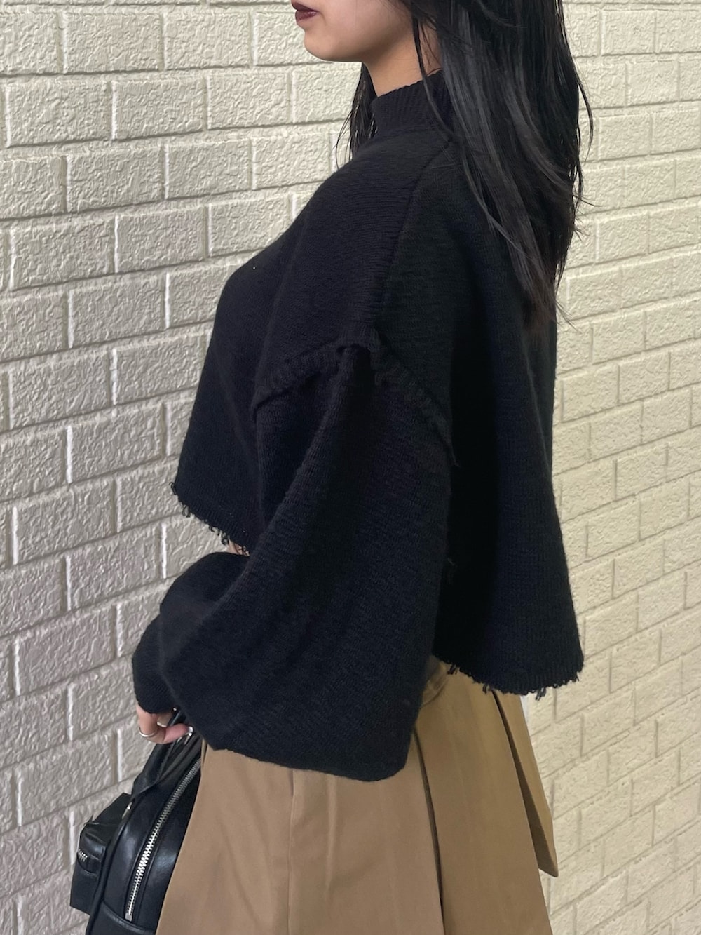 ブラック系のニット/セーター、ブラック系のブルゾン、ベージュ系のスカートを着用したレディースの秋コーディネートの8枚目の写真