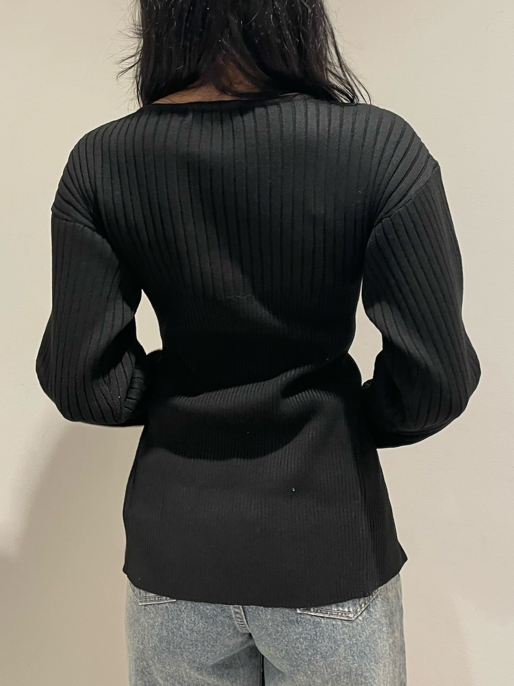 ブラック系のニット/セーター、ブルー系のデニムパンツ、ブラック系のハンドバッグを着用したレディースの冬コーディネートの6枚目の写真