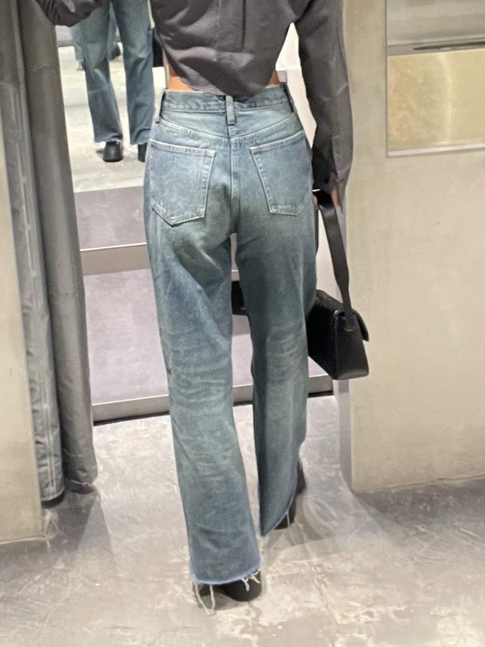 ブルー系のデニムパンツ、ブラック系のブーツ、ブラック系のハンドバッグを着用したレディースの秋コーディネートの5枚目の写真