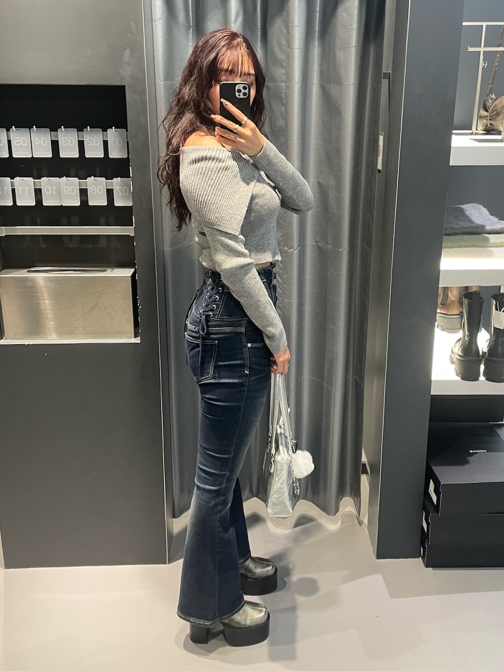 グレー系のニット/セーター、ブルー系のデニムパンツ、シルバー系のショルダーバッグを着用したレディースの冬コーディネートの2枚目の写真