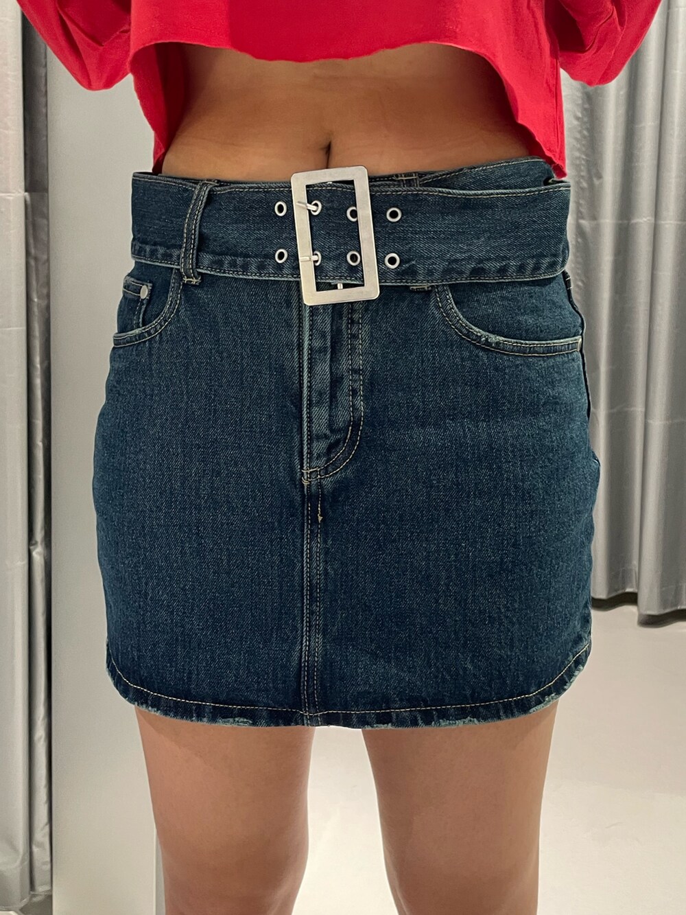 レッド系のTシャツ/カットソー、ブルー系のデニムスカート、その他のブーツを着用したレディースの秋コーディネートの7枚目の写真