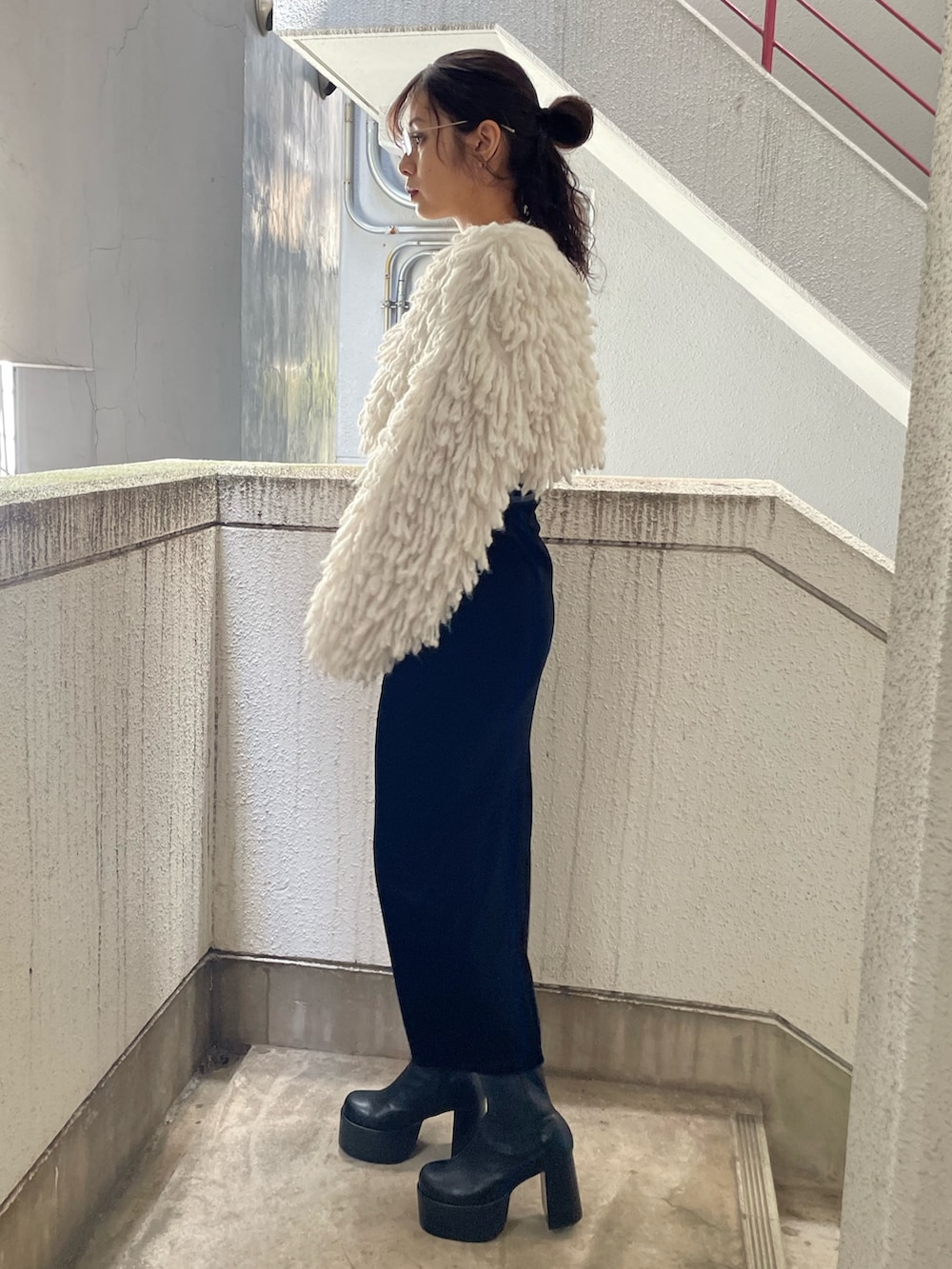 ホワイト系のニット/セーター、ブラック系のスカート、ブラック系のブーツを着用したレディースの秋コーディネートの2枚目の写真