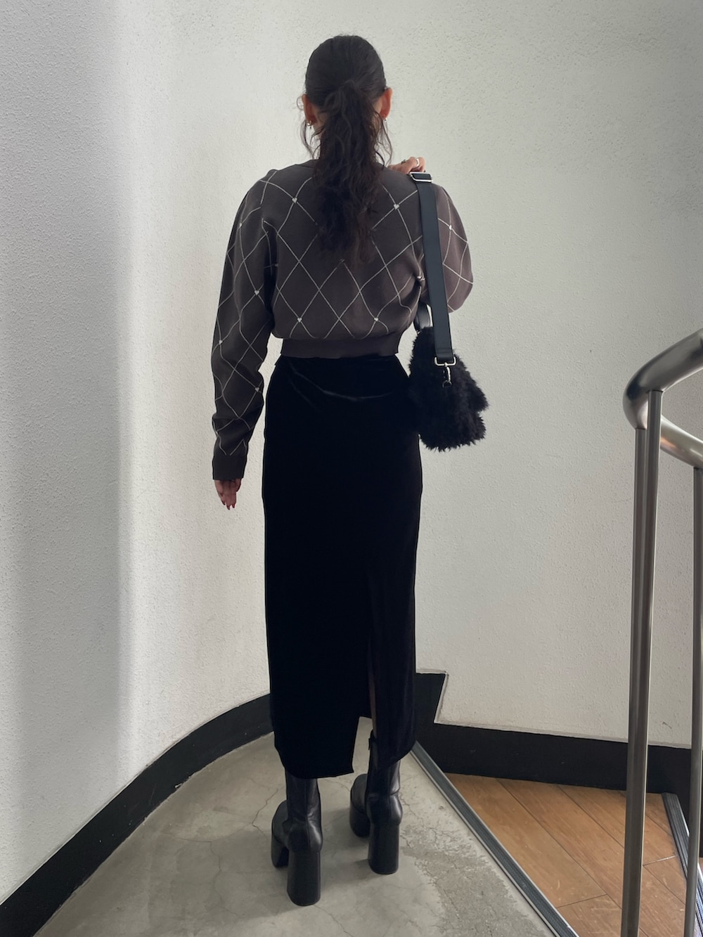 グレー系のニット/セーター、ブラック系のハンドバッグ、ブラック系のスカートを着用したレディースの秋コーディネートの3枚目の写真