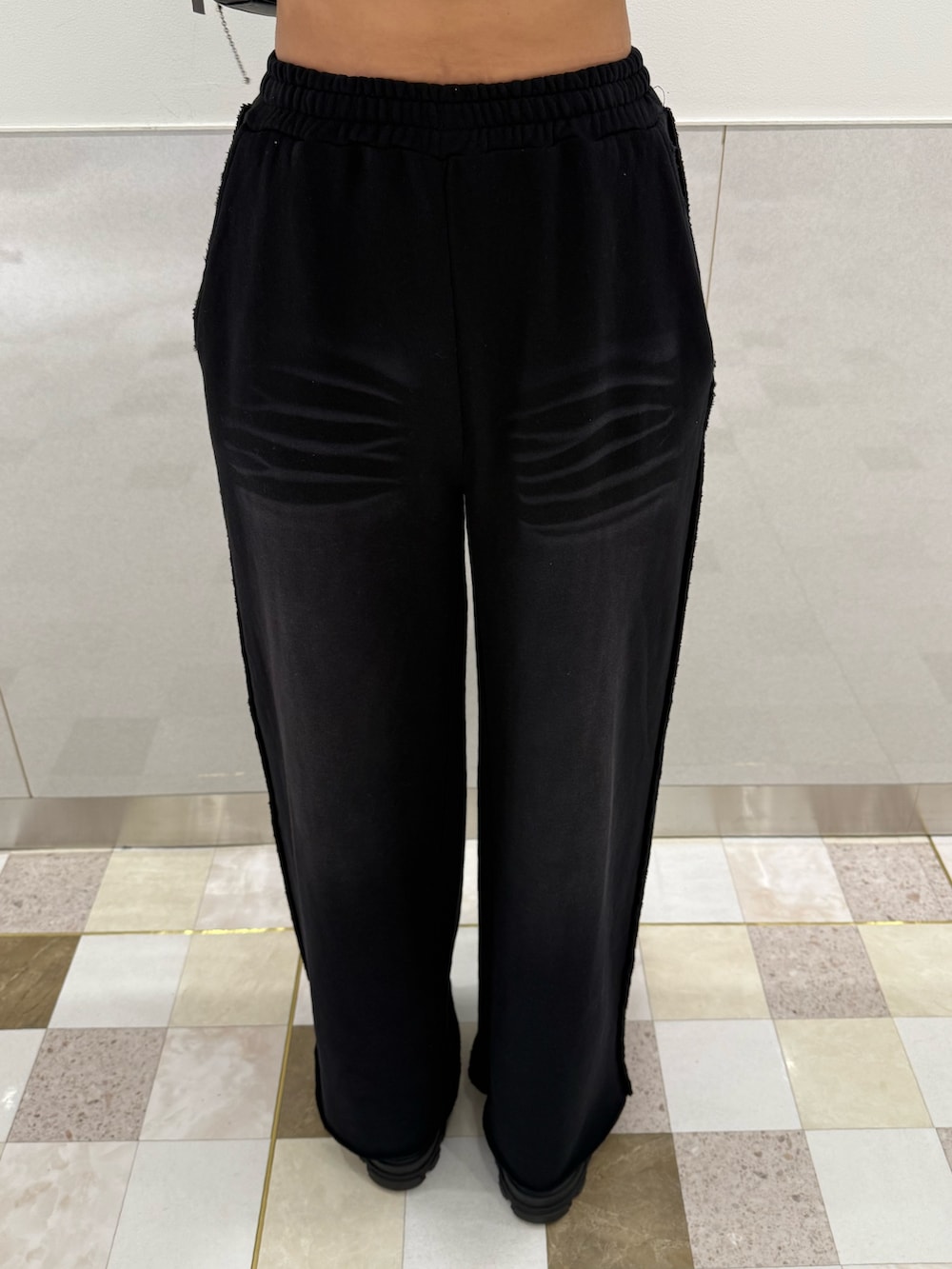 グレー系のニット/セーター、ブラック系のスウェットパンツ、ブラック系のブーツを着用したレディースの秋コーディネートの6枚目の写真