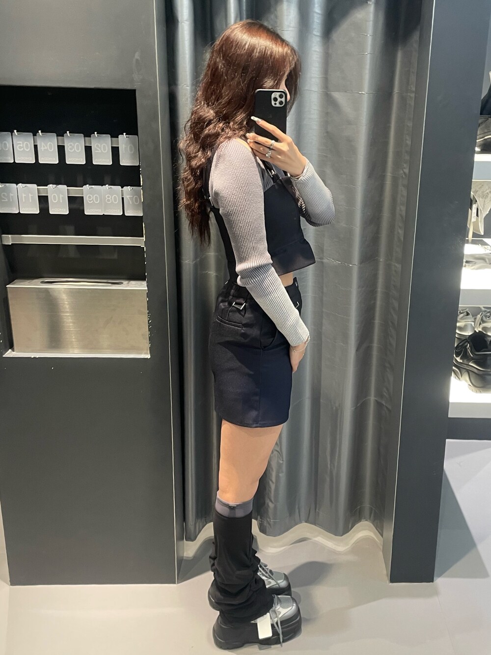 グレー系のニット/セーター、ブルー系のスカート、シルバー系のスニーカーを着用したレディースの冬コーディネートの2枚目の写真