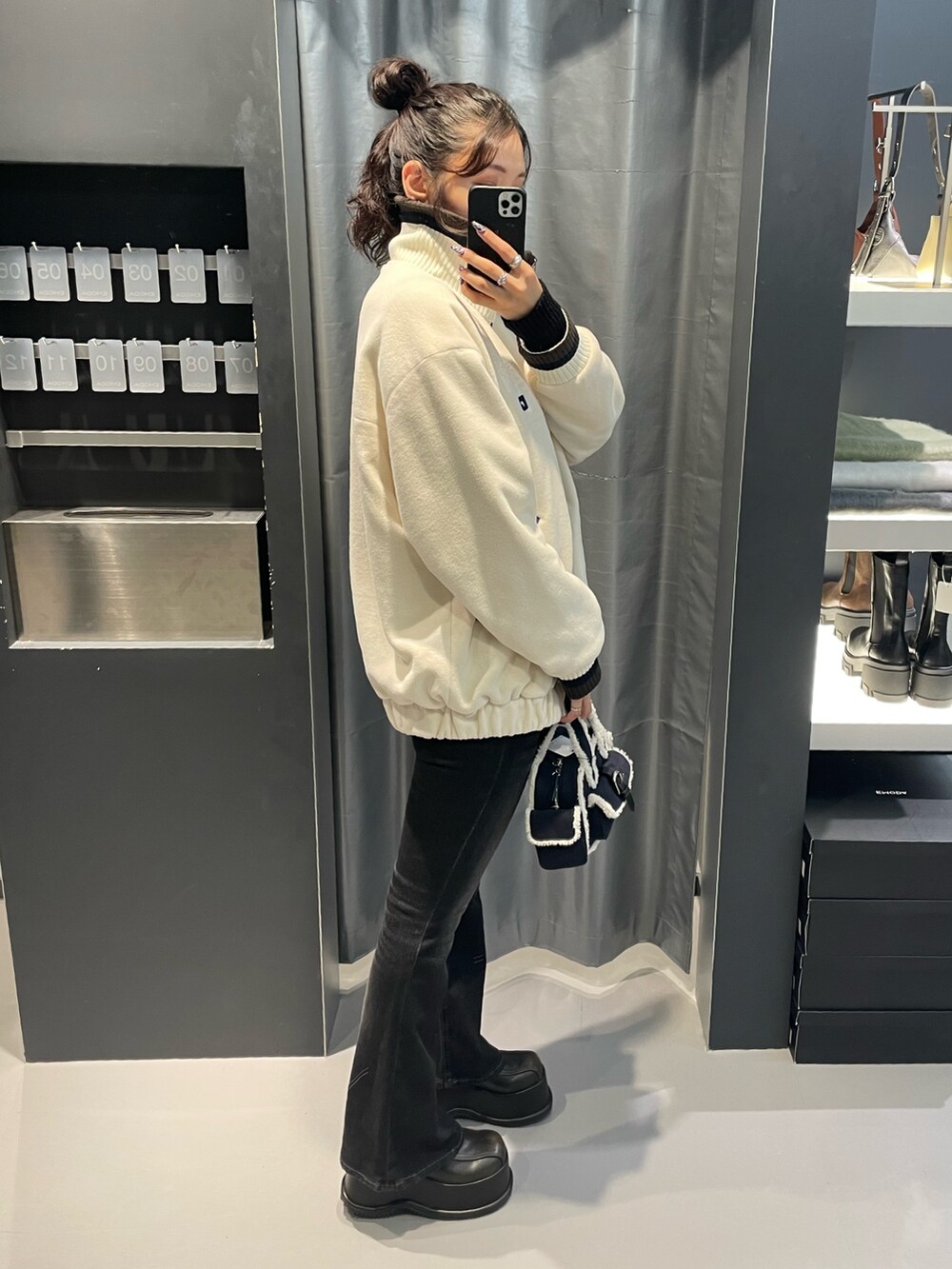 ホワイト系のブルゾン、ブルー系のハンドバッグ、ブラック系のデニムパンツを着用したレディースの秋コーディネートの2枚目の写真