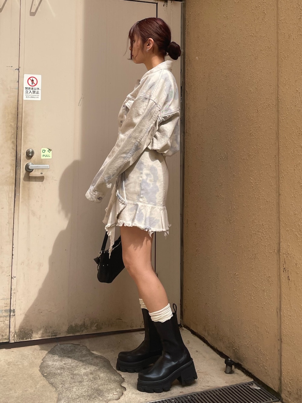 ホワイト系のデニムジャケット、ホワイト系のワンピース、ブラック系のハンドバッグを着用したレディースの春コーディネートの2枚目の写真