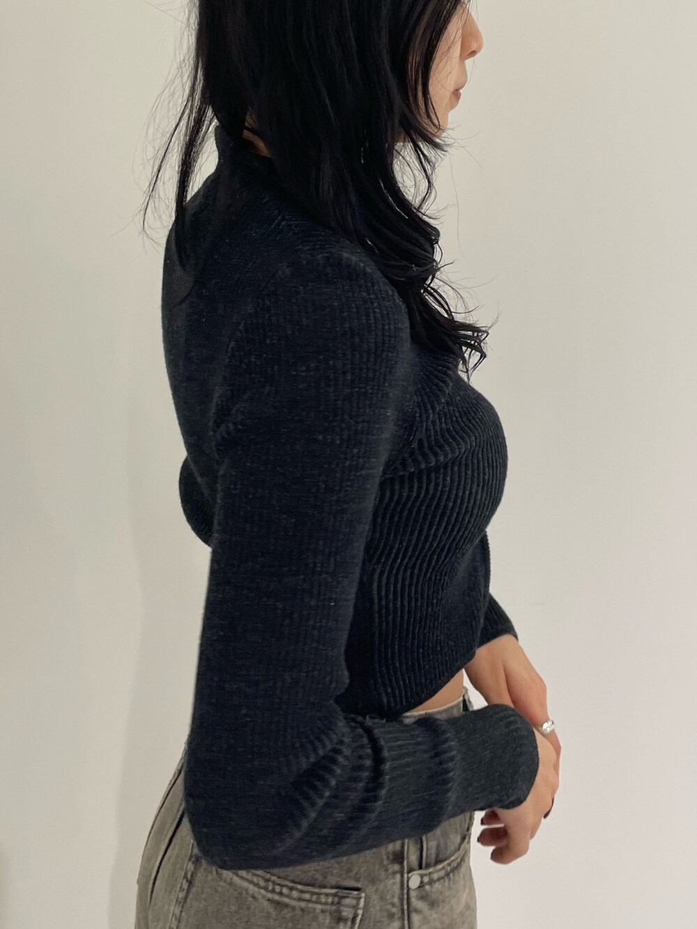 ブラック系のニット/セーター、グレー系のデニムパンツ、ブラック系のブーツを着用したレディースの春コーディネートの5枚目の写真