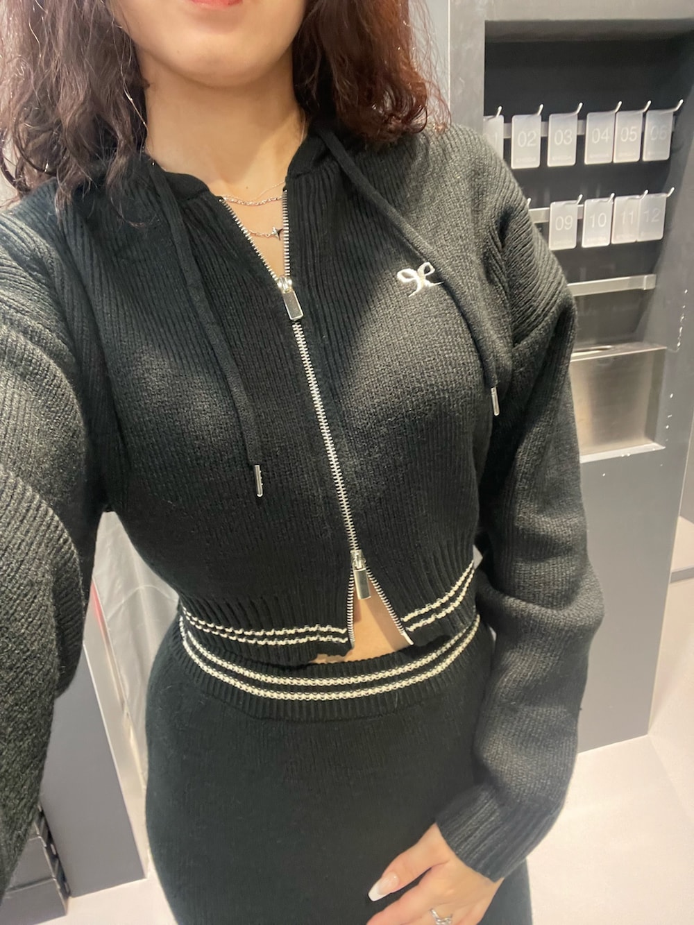 ブラック系のニット/セーター、ブラック系のスカート、シルバー系のブーツを着用したレディースの冬コーディネートの6枚目の写真