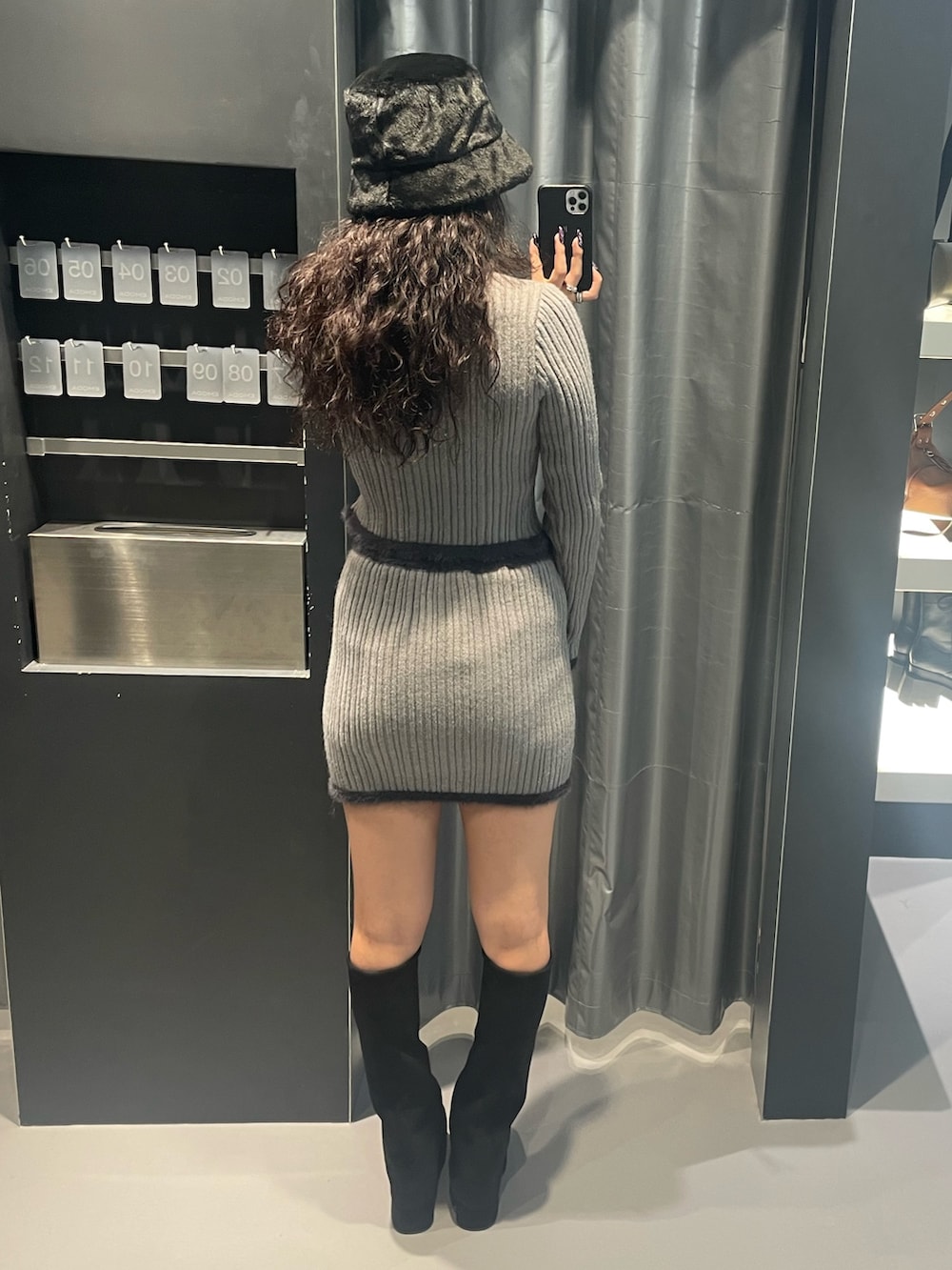 グレー系のニット/セーター、グレー系のスカート、ブラック系のブーツを着用したレディースの秋コーディネートの3枚目の写真