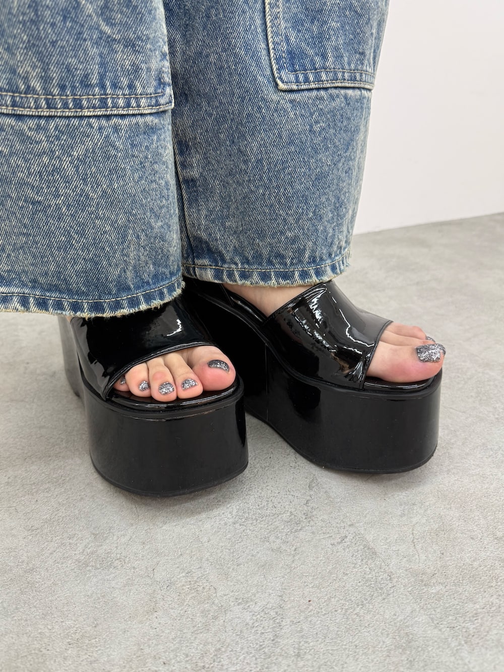 ブラック系のニット/セーター、ブルー系のデニムパンツ、ブラック系のサンダルを着用したレディースの春コーディネートの6枚目の写真