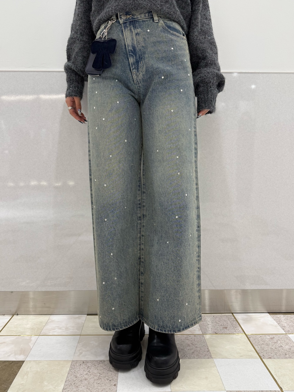 グレー系のニット/セーター、ブラック系のブーツ、ブルー系のデニムパンツを着用したレディースの冬コーディネートの6枚目の写真