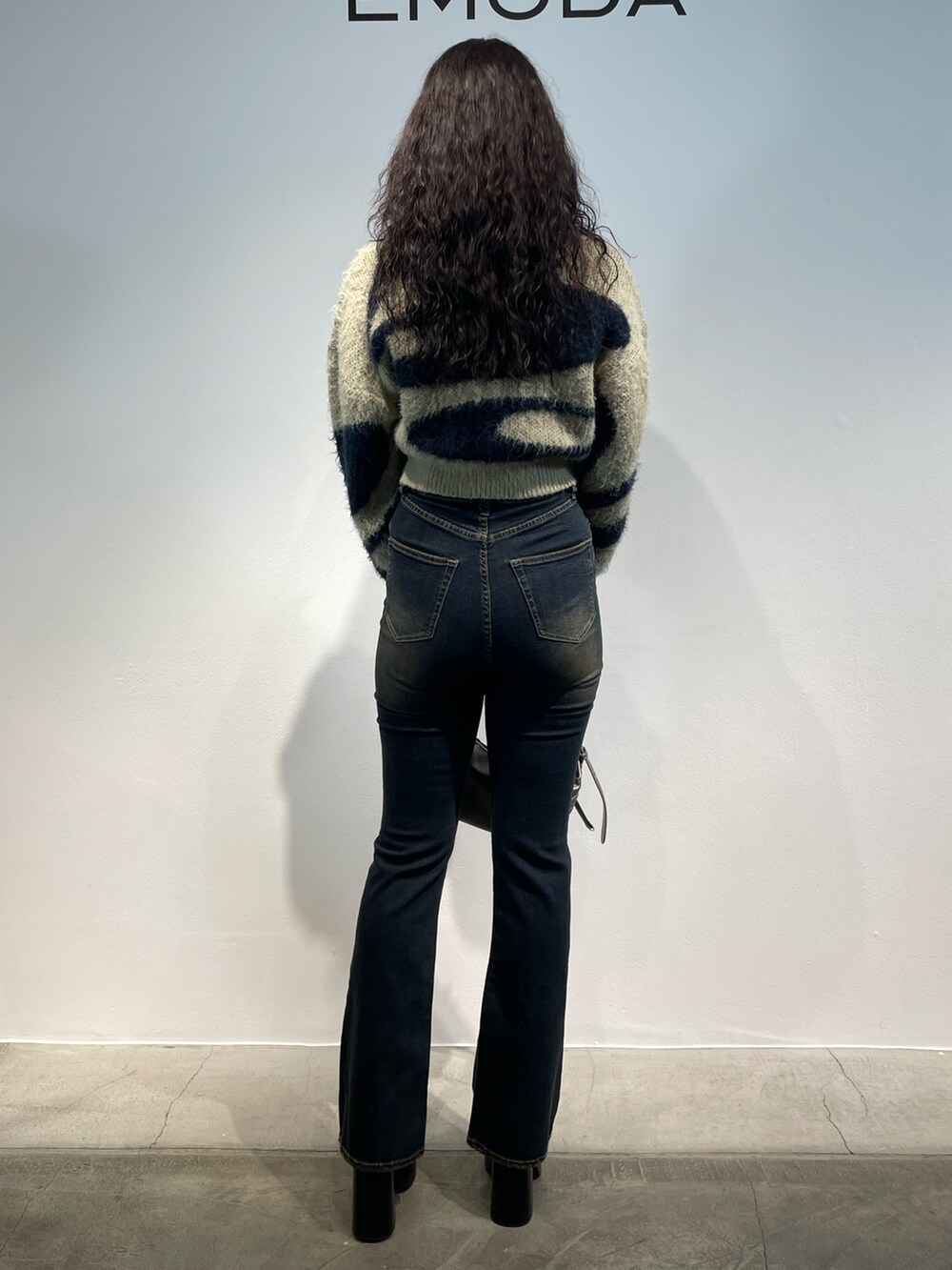 ブルー系のニット/セーター、ブルー系のデニムパンツ、シルバー系のハンドバッグを着用したレディースの秋コーディネートの3枚目の写真