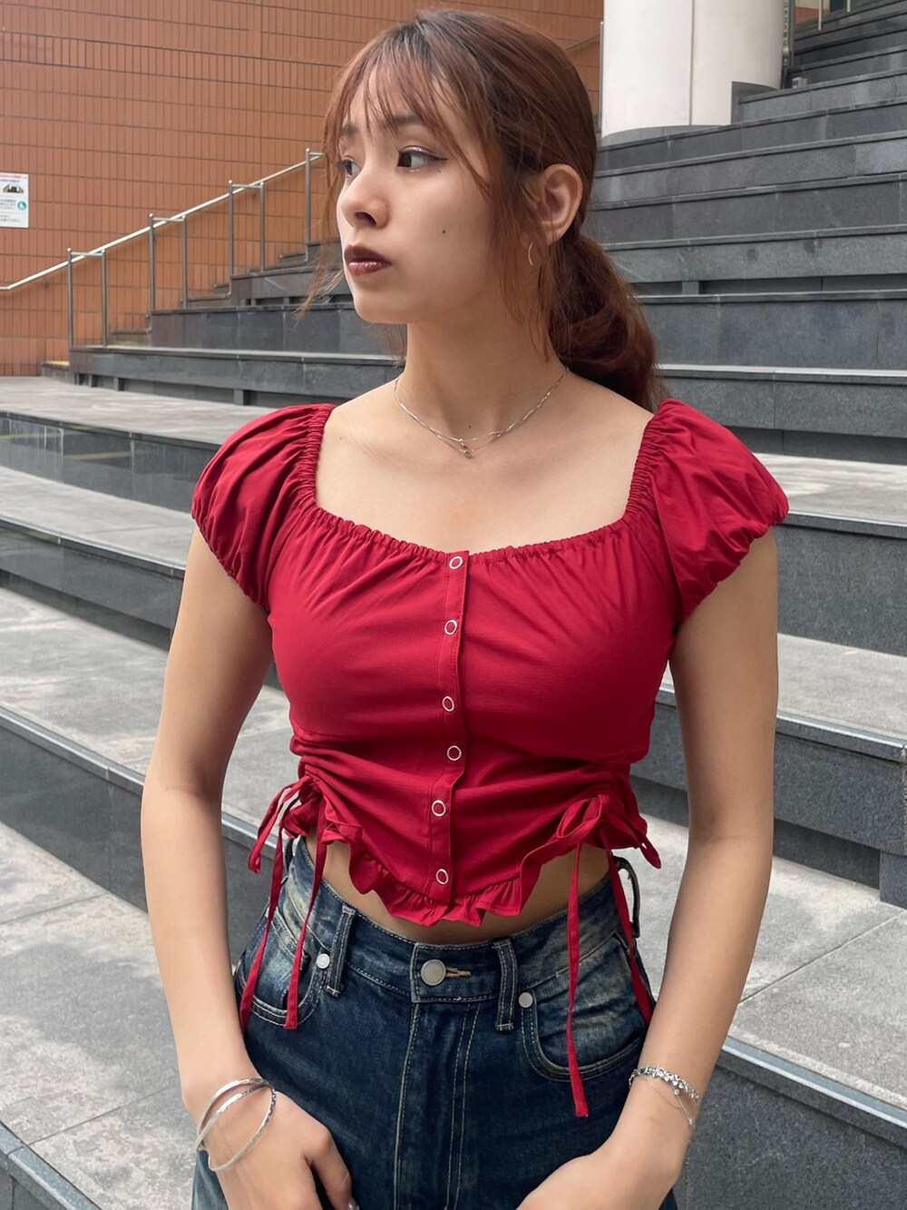 レッド系のTシャツ/カットソー、ブルー系のデニムパンツ、ブラック系のハンドバッグを着用したレディースの春コーディネートの4枚目の写真