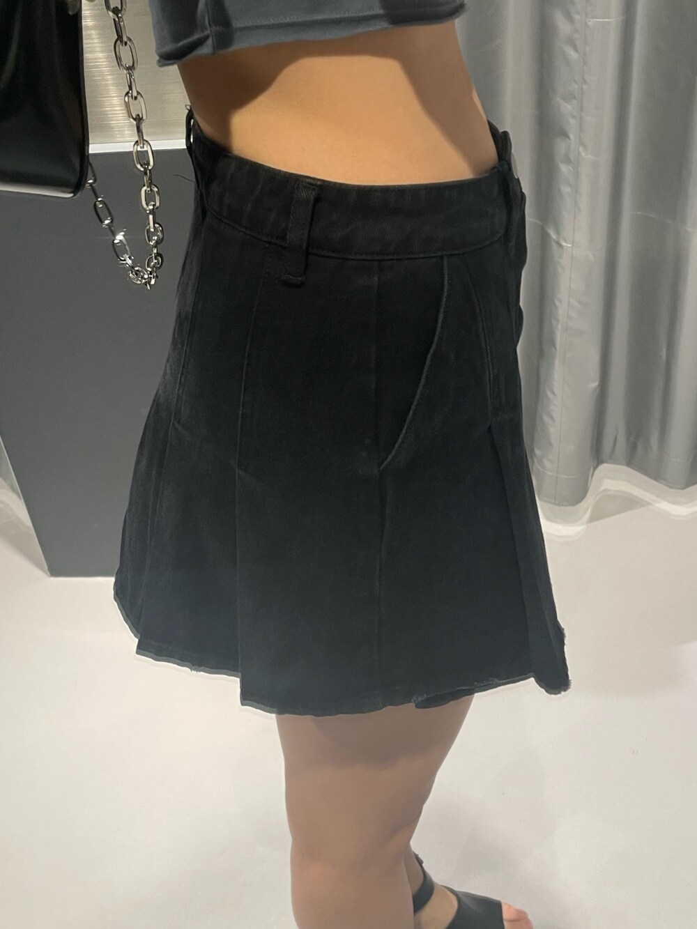 グレー系のTシャツ/カットソー、ブラック系のデニムスカート、ブラック系のショルダーバッグを着用したレディースの春コーディネートの7枚目の写真