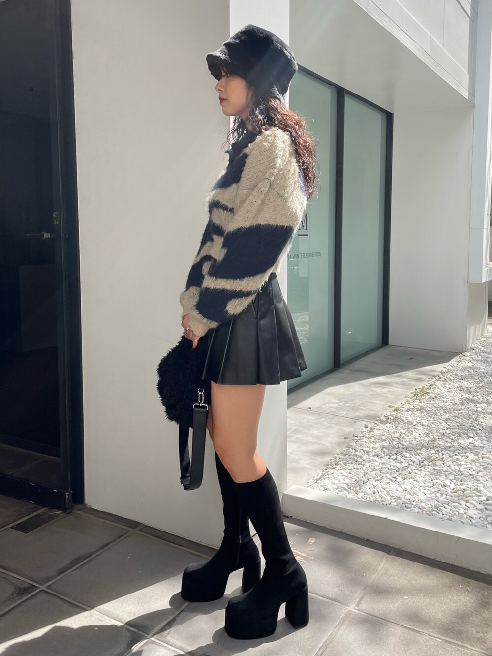 ブルー系のニット/セーター、ブラック系のスカート、ブラック系のハンドバッグを着用したレディースの秋コーディネートの2枚目の写真