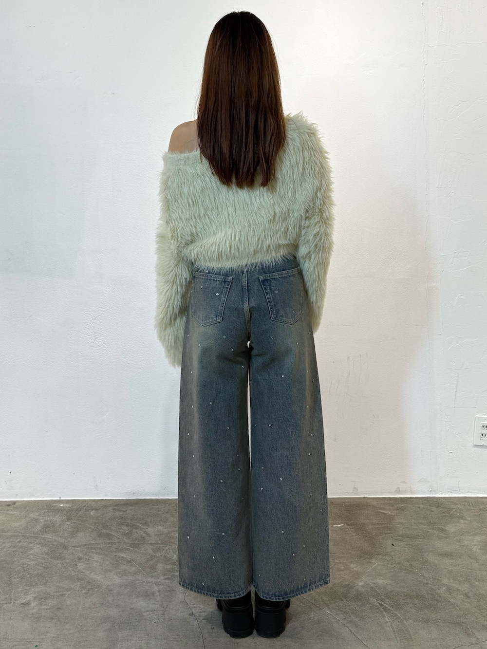 ホワイト系のニット/セーター、ブルー系のデニムパンツ、ブラック系のブーツを着用したレディースの冬コーディネートの3枚目の写真