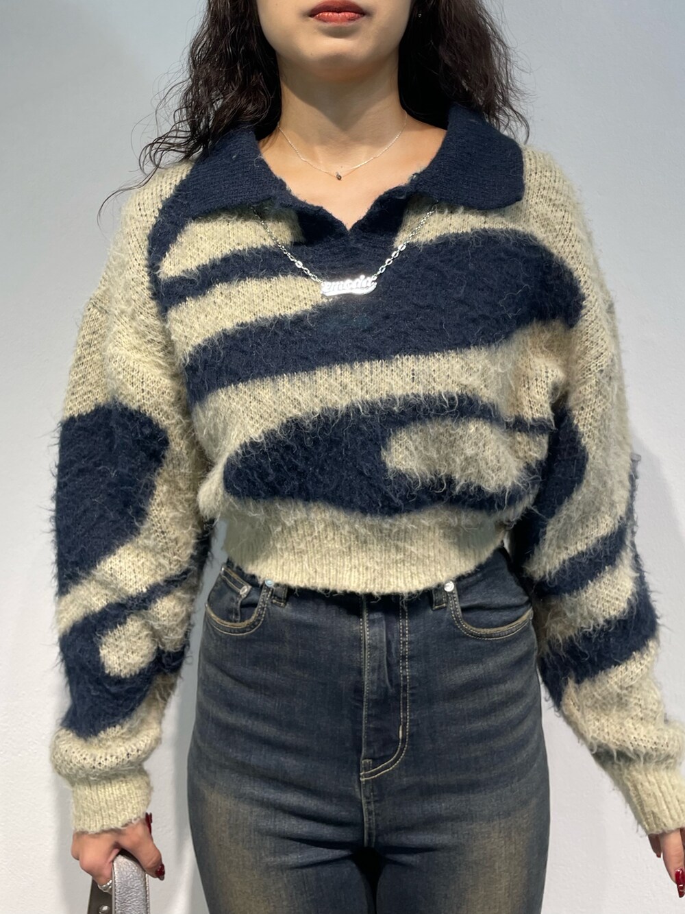 ブルー系のニット/セーター、ブラック系のスカート、ブラック系のハンドバッグを着用したレディースの秋コーディネートの4枚目の写真