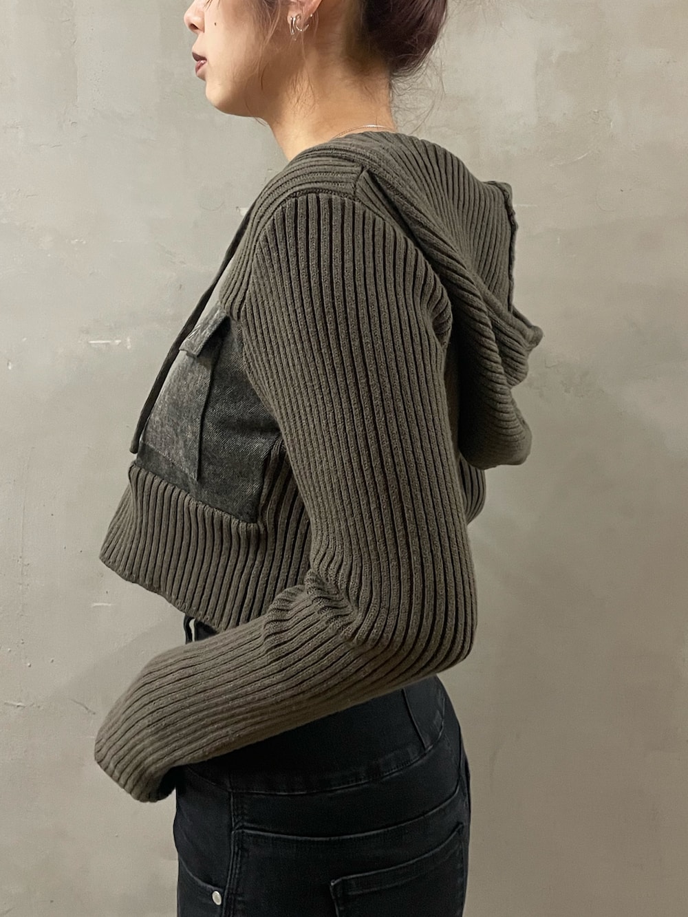 グリーン系のニット/セーター、ブラック系のデニムパンツ、ブラック系のサンダルを着用したレディースの春コーディネートの5枚目の写真