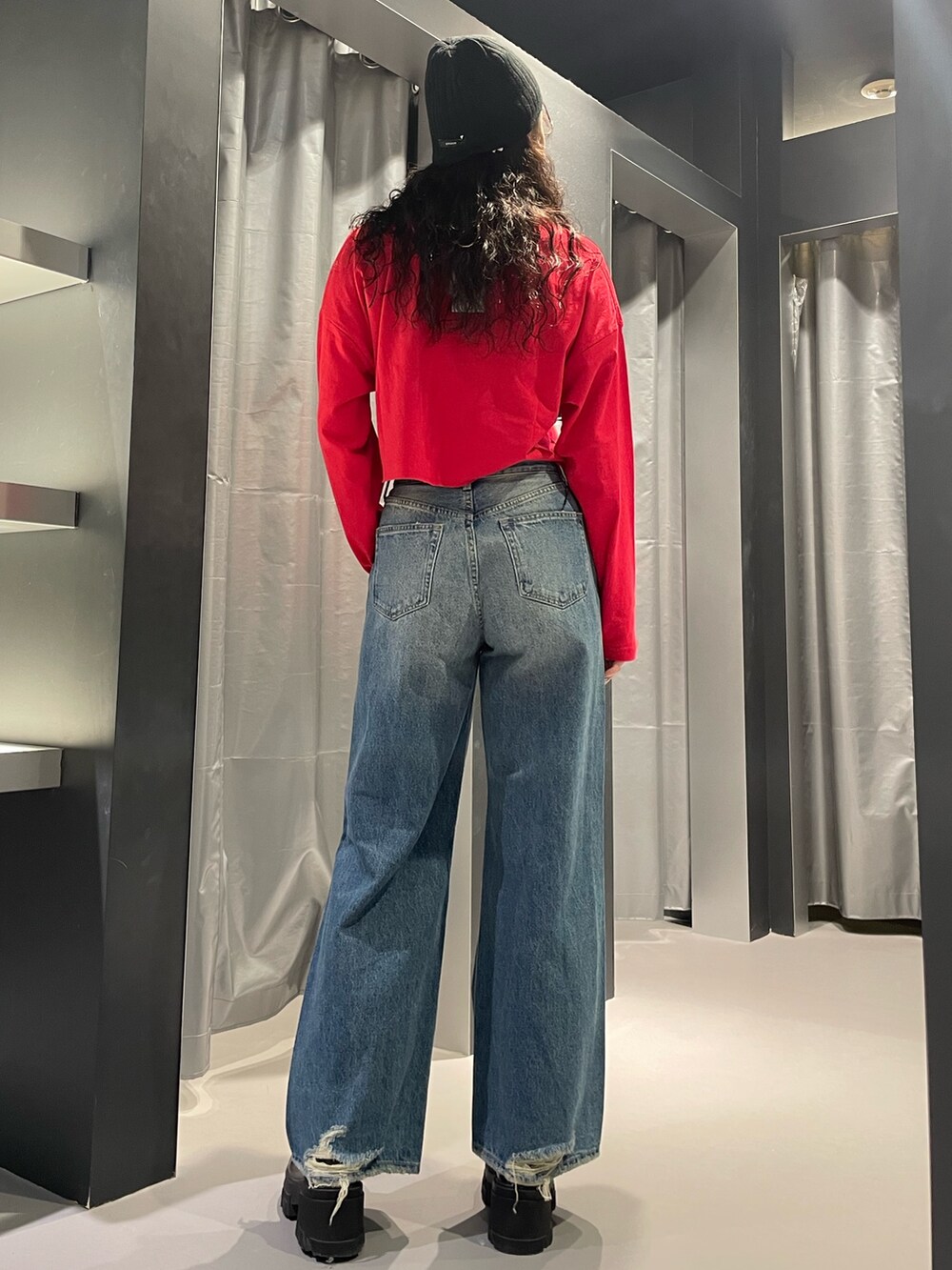 レッド系のTシャツ/カットソー、ブルー系のデニムパンツ、ブラック系のブーツを着用したレディースの秋コーディネートの3枚目の写真