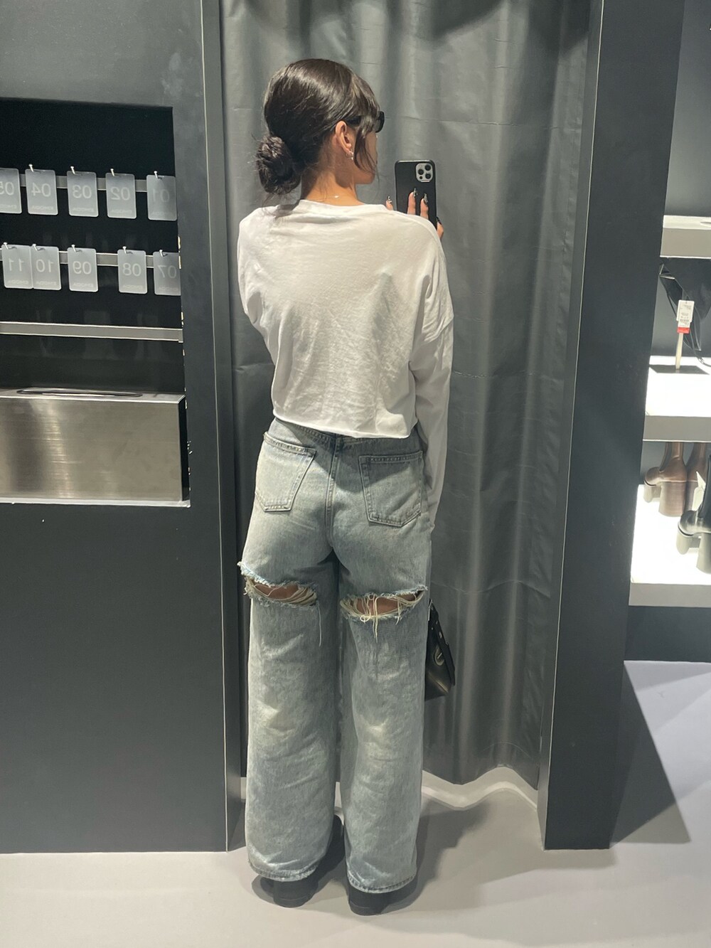 ホワイト系のTシャツ/カットソー、ブルー系のデニムパンツ、ブラック系のハンドバッグを着用したレディースの秋コーディネートの3枚目の写真