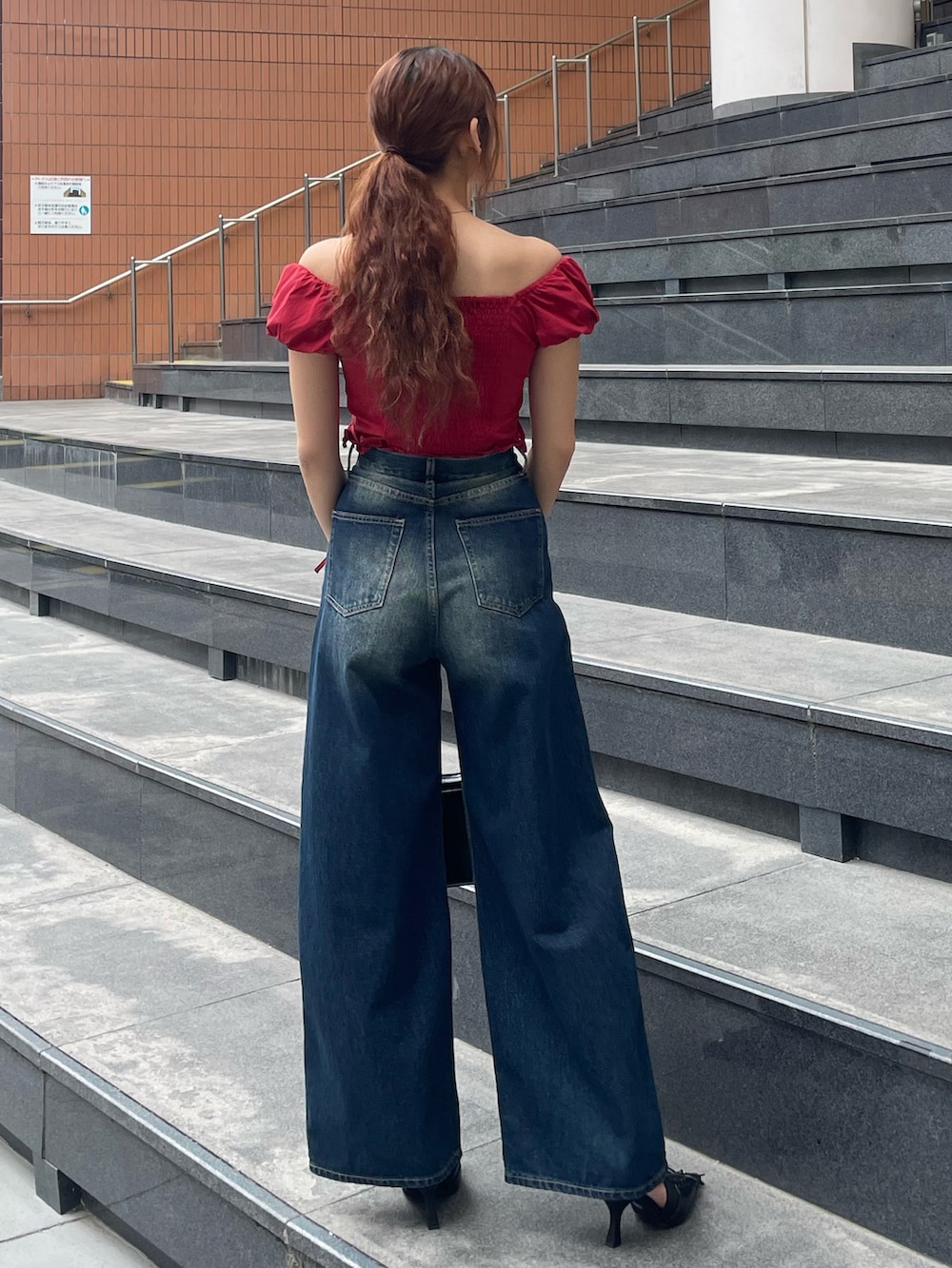 レッド系のTシャツ/カットソー、ブルー系のデニムパンツ、ブラック系のハンドバッグを着用したレディースの春コーディネートの3枚目の写真