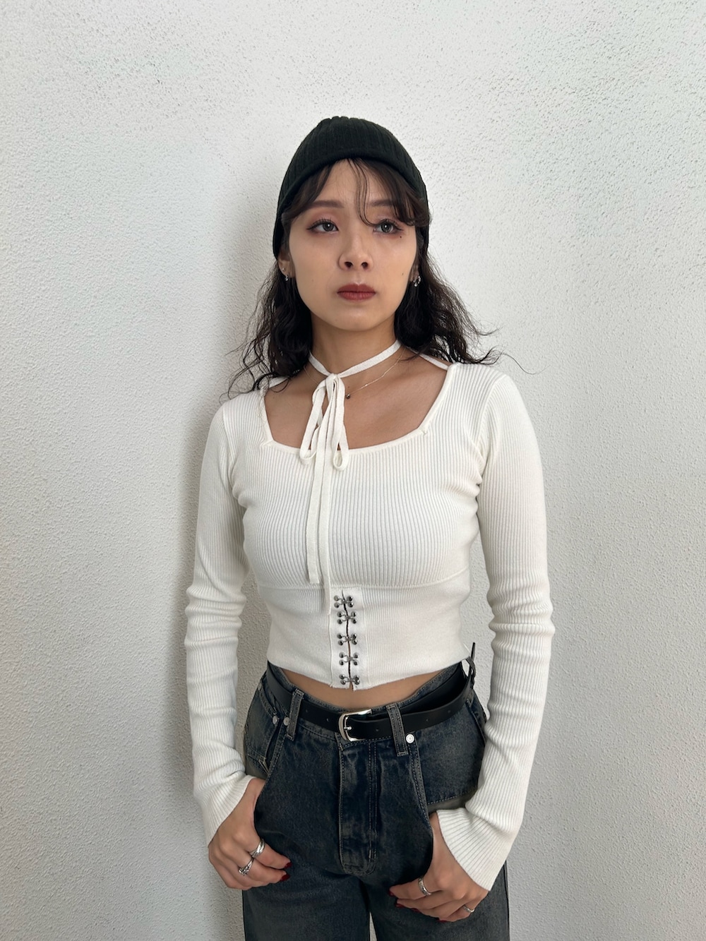 ホワイト系のニット/セーター、ブラック系のハンドバッグ、ブルー系のデニムパンツを着用したレディースの秋コーディネートの4枚目の写真