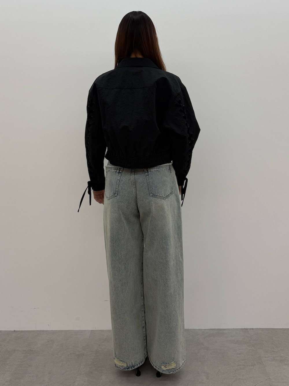 ブラック系のブルゾン、ホワイト系のTシャツ/カットソー、ブルー系のデニムパンツを着用したレディースの冬コーディネートの3枚目の写真