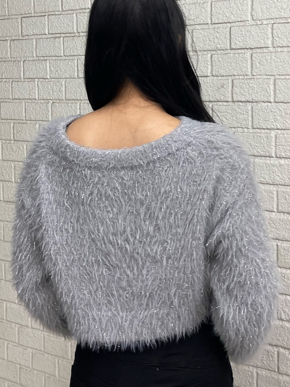 グレー系のニット/セーター、ブラック系のデニムパンツ、ブラック系のブーツを着用したレディースの冬コーディネートの6枚目の写真