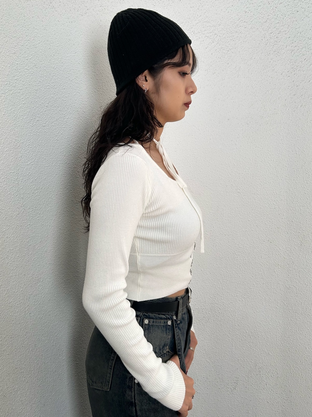 ホワイト系のニット/セーター、ブラック系のハンドバッグ、ブルー系のデニムパンツを着用したレディースの秋コーディネートの5枚目の写真