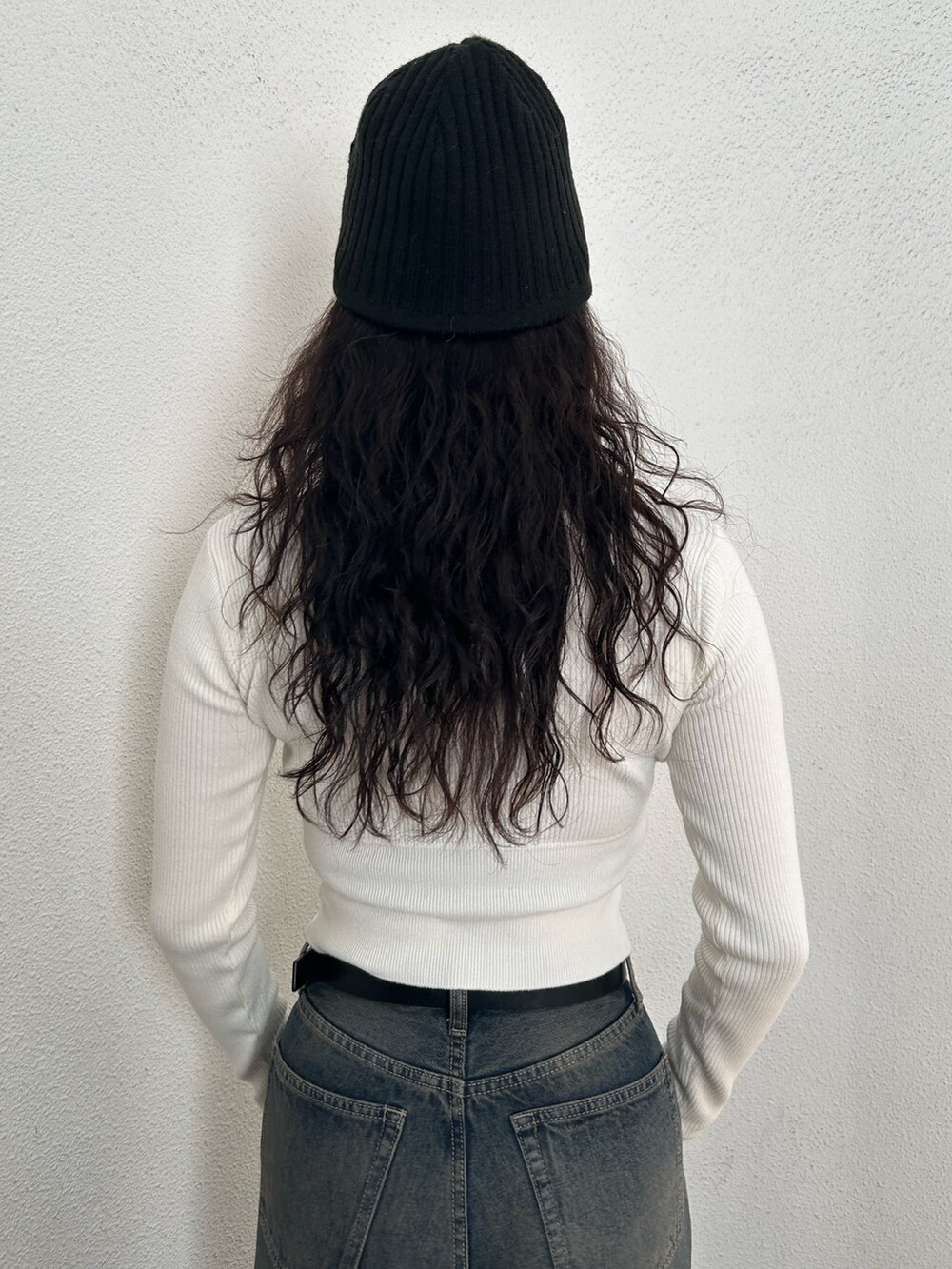 ホワイト系のニット/セーター、ブラック系のハンドバッグ、ブルー系のデニムパンツを着用したレディースの秋コーディネートの6枚目の写真