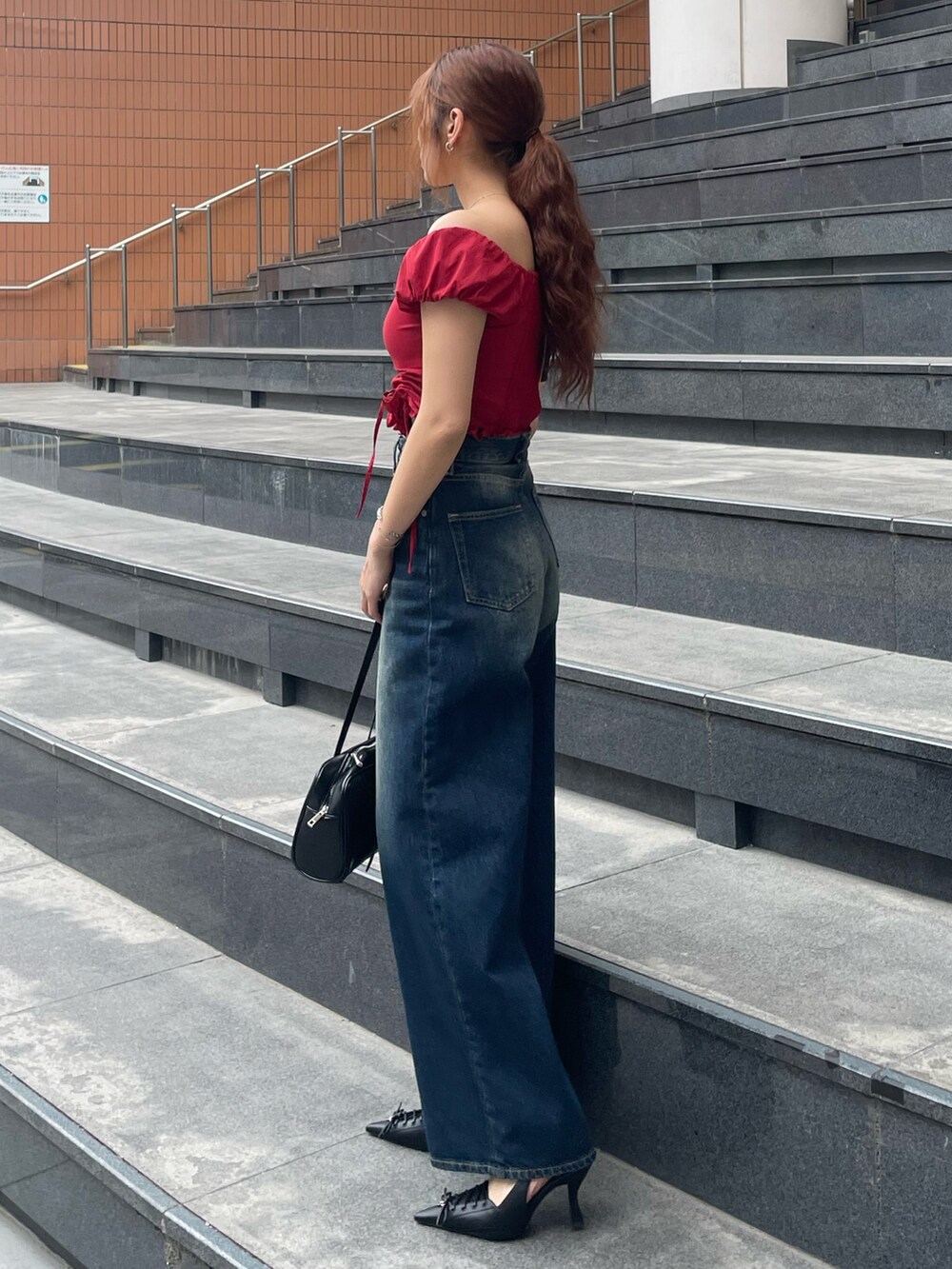 レッド系のTシャツ/カットソー、ブルー系のデニムパンツ、ブラック系のハンドバッグを着用したレディースの春コーディネートの2枚目の写真