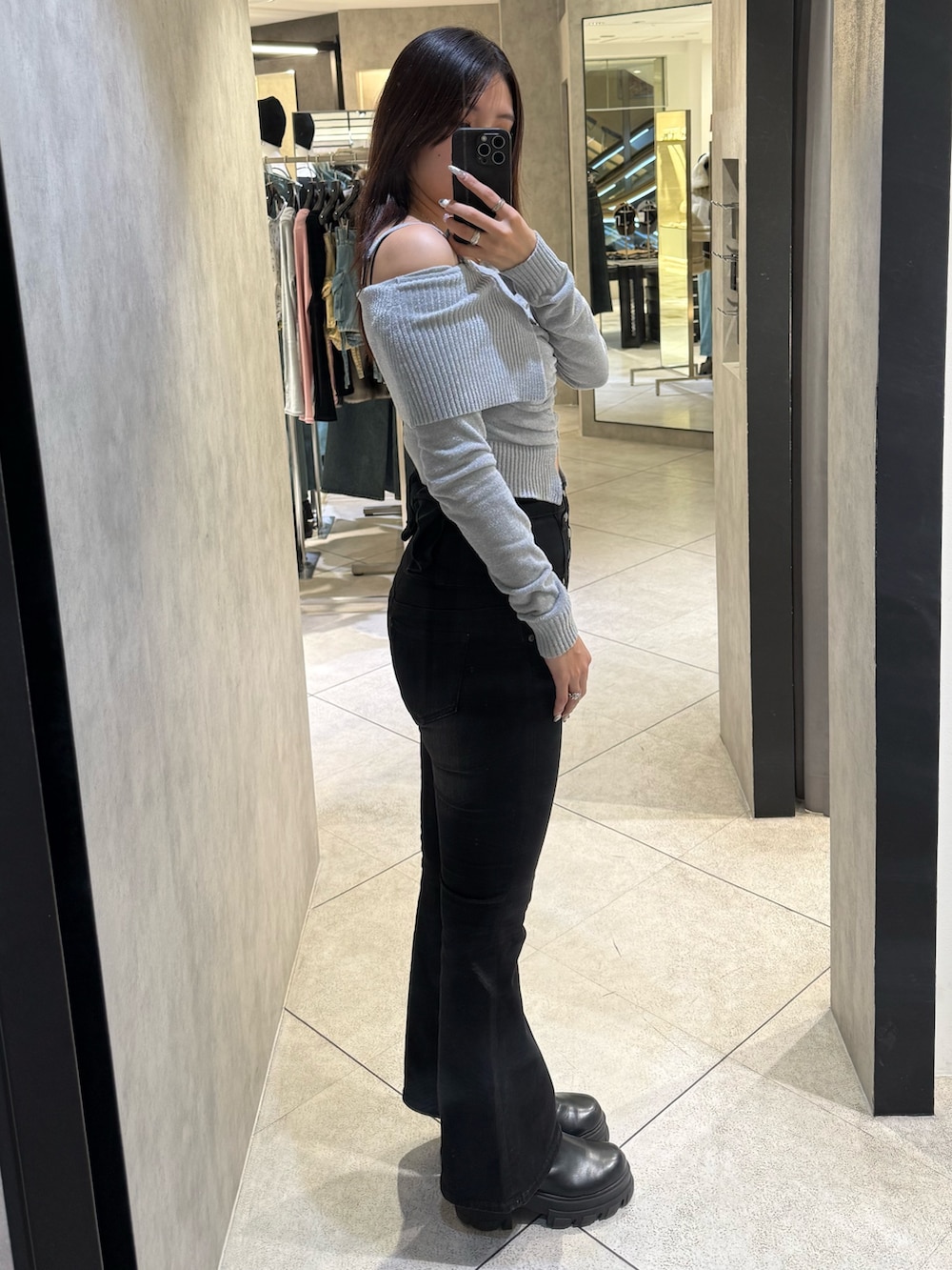 グレー系のニット/セーター、ブラック系のデニムパンツ、ブラック系のブーツを着用したレディースの春コーディネートの2枚目の写真