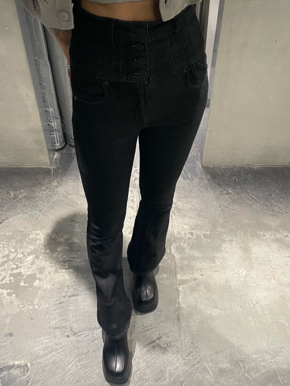 グレー系のニット/セーター、ブラック系のデニムパンツ、ブラック系のブーツを着用したレディースの秋コーディネートの4枚目の写真