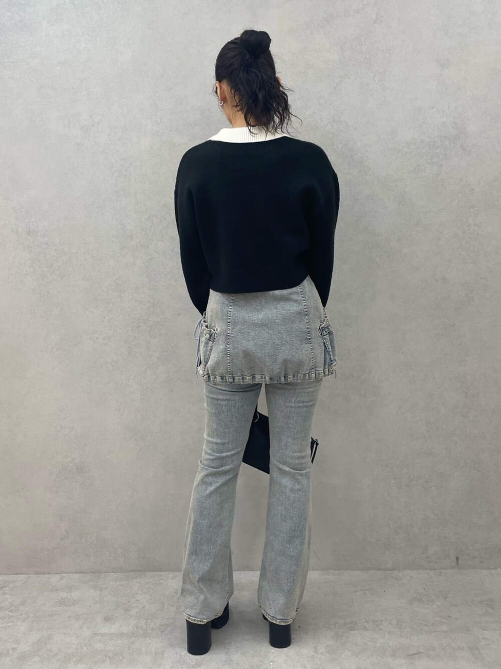 ブラック系のニット/セーター、ブルー系のデニムパンツ、ブラック系のショルダーバッグを着用したレディースの夏コーディネートの3枚目の写真