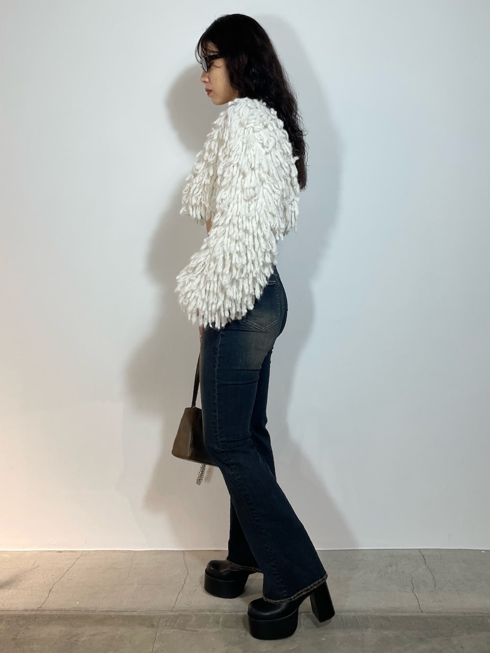 ホワイト系のニット/セーター、ブルー系のデニムパンツ、ブラウン系のショルダーバッグを着用したレディースの秋コーディネートの2枚目の写真