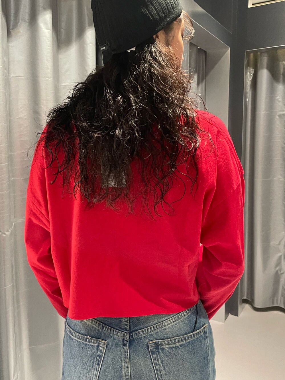 レッド系のTシャツ/カットソー、ブルー系のデニムパンツ、ブラック系のブーツを着用したレディースの秋コーディネートの6枚目の写真