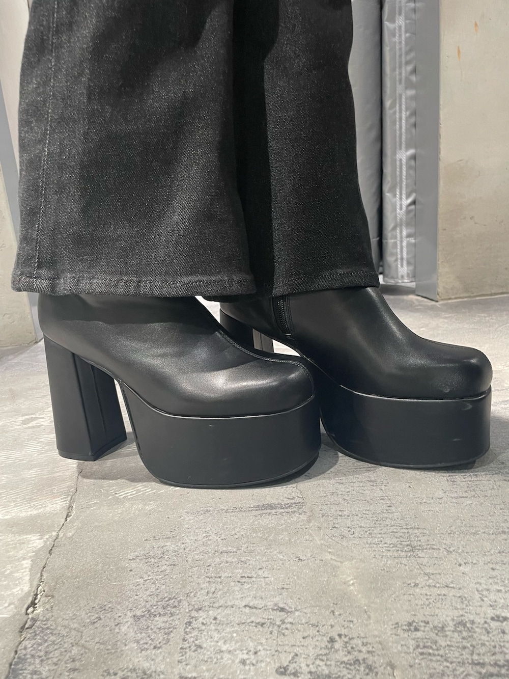 グレー系のニット/セーター、ブラック系のデニムパンツ、ブラック系のブーツを着用したレディースの秋コーディネートの5枚目の写真