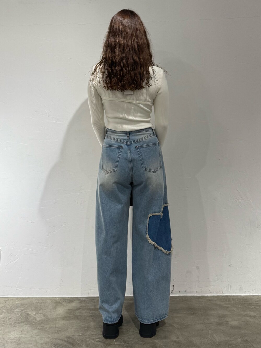 ホワイト系のニット/セーター、ブルー系のデニムパンツ、ブラック系のハンドバッグを着用したレディースの秋コーディネートの3枚目の写真