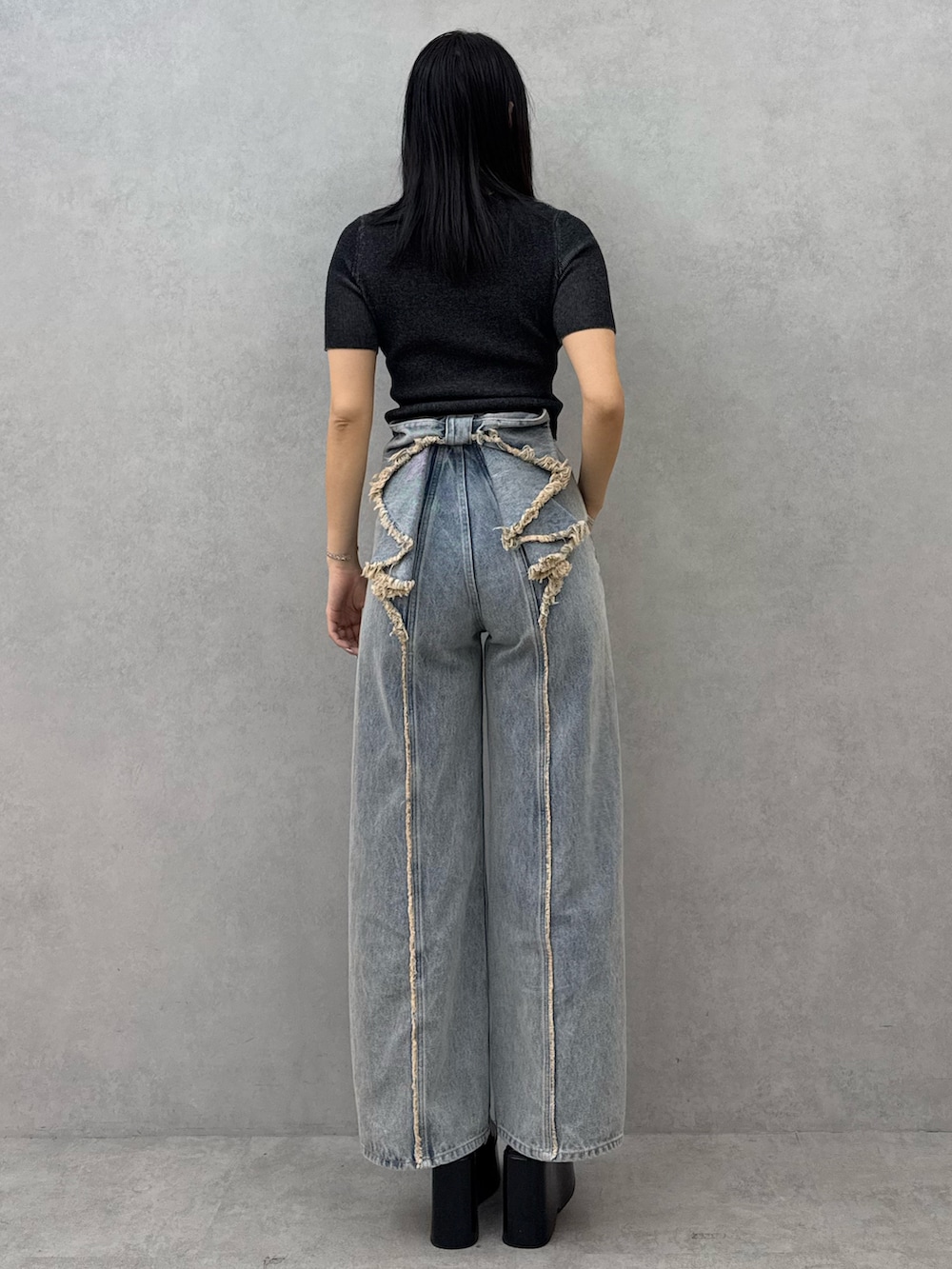 ブラック系のニット/セーター、ブルー系のデニムパンツ、ブラック系のサンダルを着用したレディースの春コーディネートの3枚目の写真